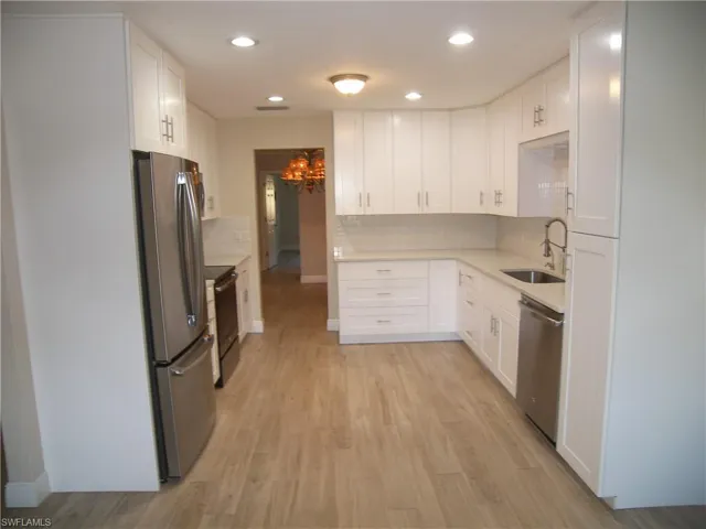 Kitchen featuring sink, stainless steel appliances, white cabinetry, and light hardwood / wood-style flooring