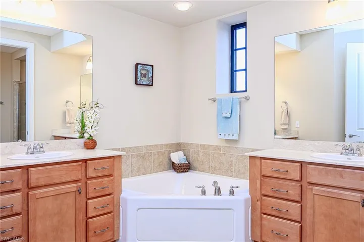 Full bath featuring a garden tub, two vanities, and a sink