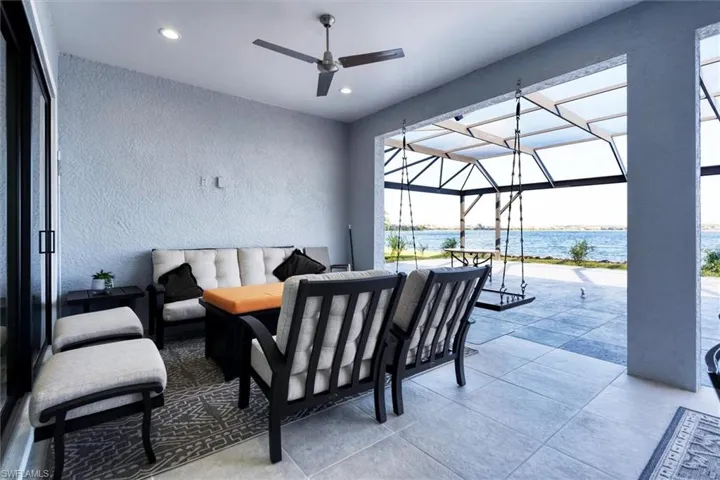 View of patio with an outdoor hangout area, a water view, ceiling fan, and a lanai