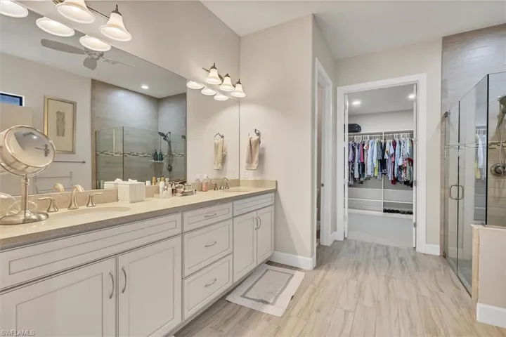 Bathroom with ceiling fan, vanity, and an enclosed shower