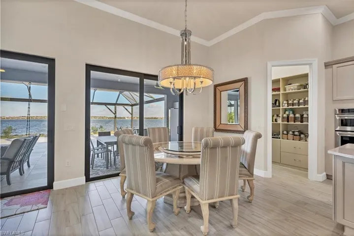 Dining space with lofted ceiling, a water view, built in shelves, ornamental molding, and a chandelier