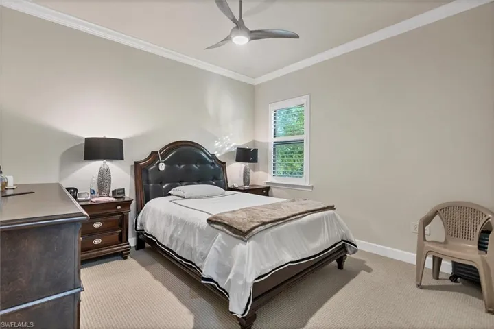 Bedroom with light carpet, ceiling fan, and ornamental molding