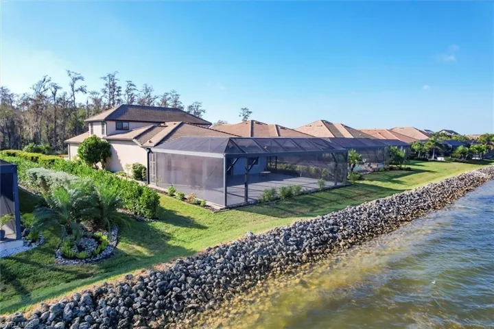 Rear view of house with a patio, a yard, a water view, and glass enclosure