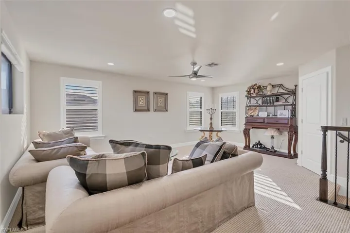 Living room with ceiling fan, light colored carpet, and a healthy amount of sunlight