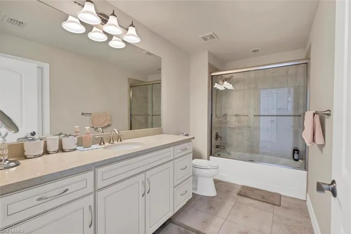 Full bathroom with tile patterned flooring, vanity, toilet, and bath / shower combo with glass door