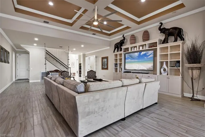 Living room featuring ceiling fan, crown molding, and coffered ceiling
