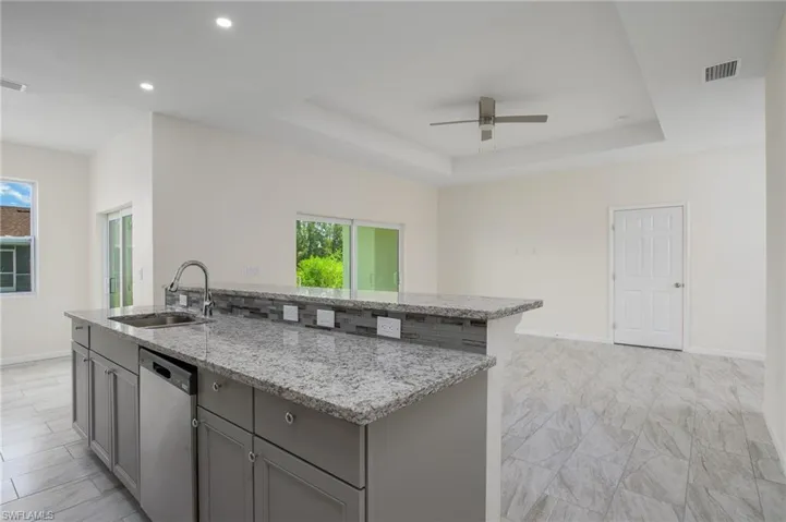 Kitchen featuring dishwasher, gray cabinetry, ceiling fan, healthy amount of natural light, plenty of counter pace, and recessed lighting