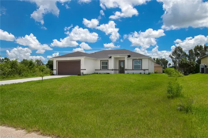 Ranch-style home featuring stucco siding, concrete driveway, an attached garage, and a front lawn