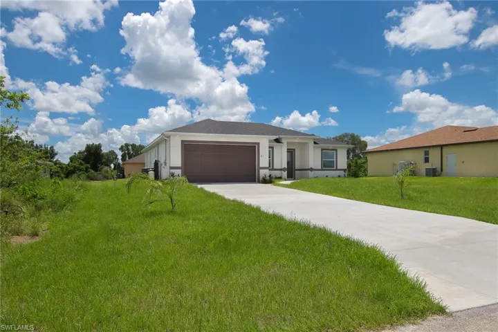 Ranch-style house featuring an attached garage, stucco siding, concrete driveway, and water equipment.