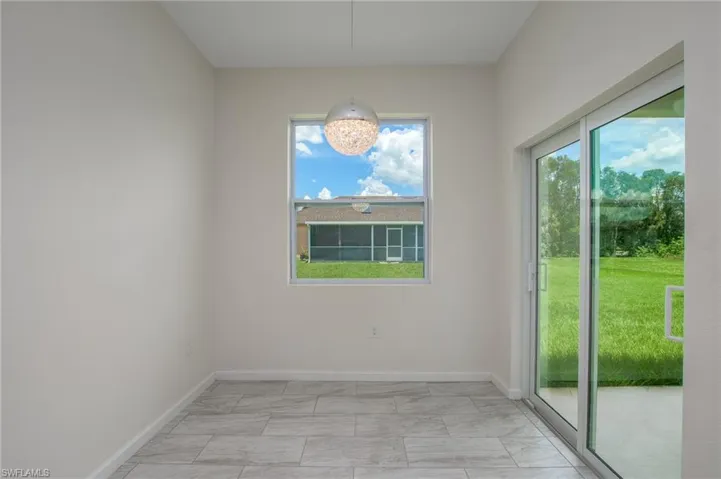 Unfurnished dining area with light marble finish tile floors, a chandelier, and access to open lanai