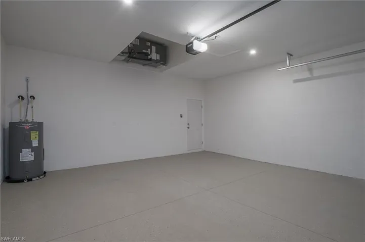 Garage featuring water heater, a garage door opener, a/c unit, and recessed lighting