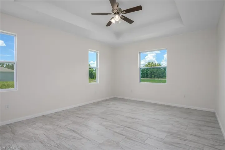 Master bedroom with plenty of healthy lighting, tray ceiling and a ceiling fan