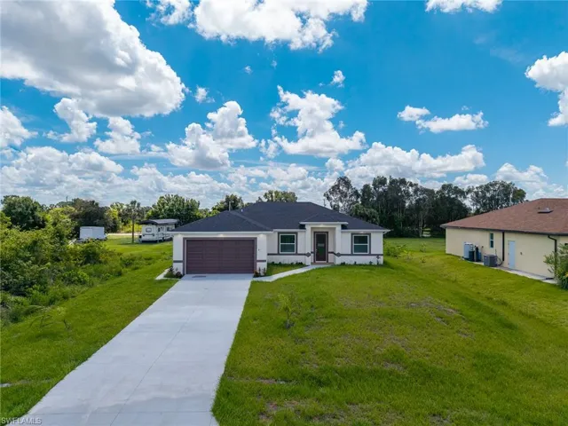 View of front of house featuring a garage, driveway, a front yard, and stucco siding