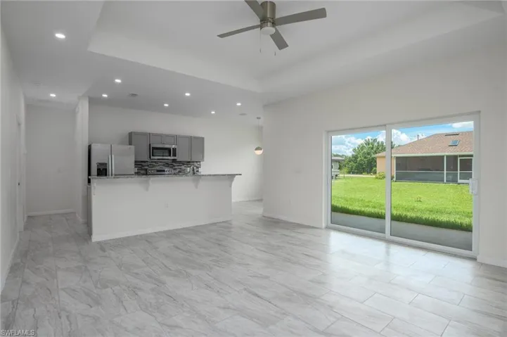 Living room featuring ceiling fan, recessed lighting, and a tray ceiling, access to backyard