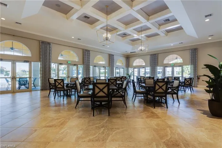 Dining area featuring coffered ceiling, crown molding, a wealth of natural light, and an inviting chandelier