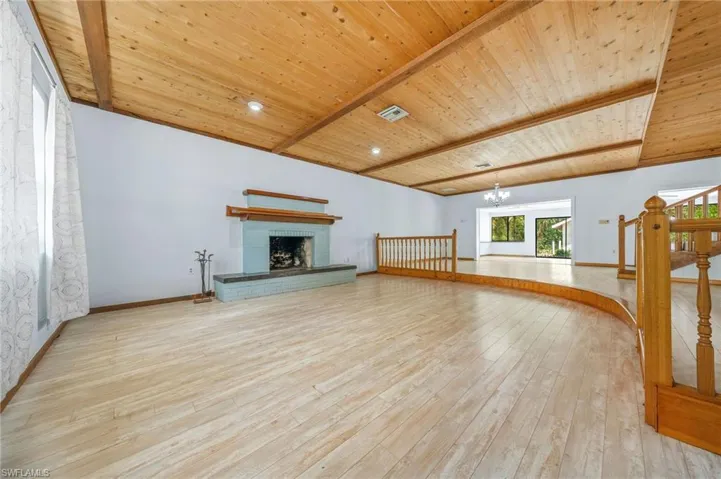 Unfurnished living room featuring a fireplace, wood ceiling, wood-type flooring, baseboards, and beam ceiling
