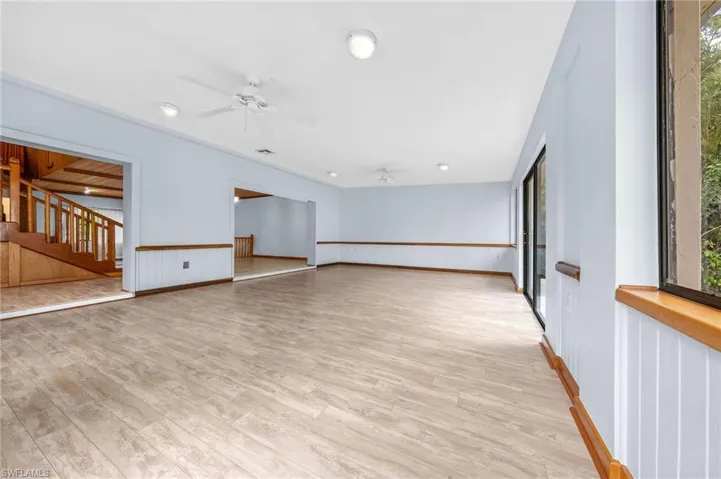 Spare room with light wood finished floors, a ceiling fan, and stairs