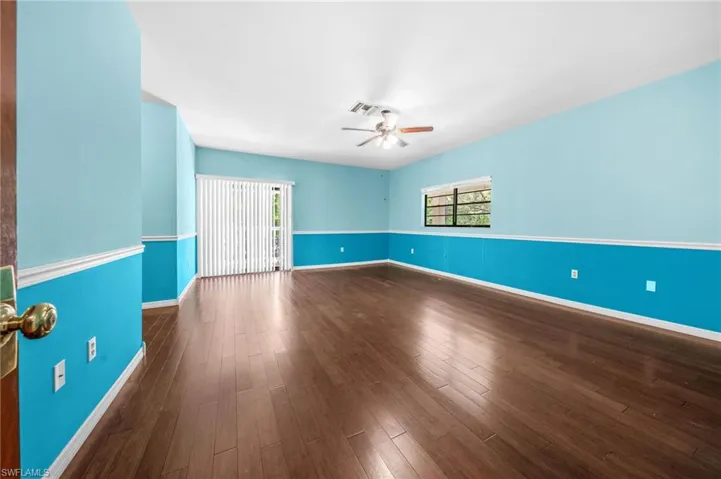 Empty room with visible vents, ceiling fan, baseboards, and dark wood-style floors