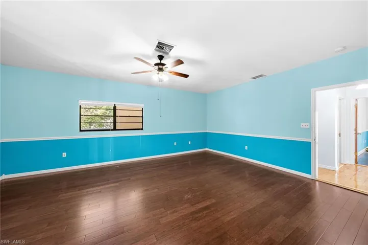 Spare room featuring visible vents, baseboards, a ceiling fan, and wood finished floors