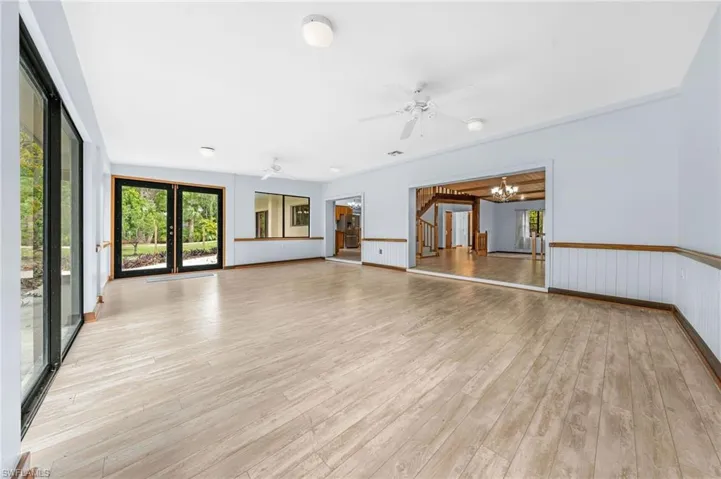 Unfurnished living room featuring visible vents, light wood-type flooring, and ceiling fan with notable chandelier