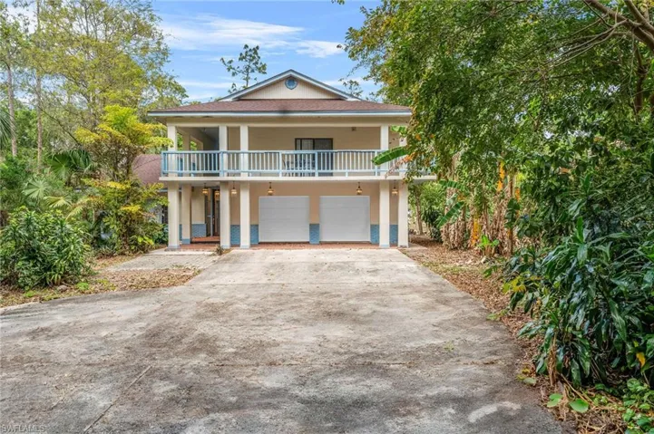 Raised beach house with concrete driveway, a garage, and stucco siding