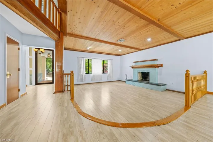 Unfurnished living room featuring beamed ceiling, hardwood / wood-style flooring, an inviting chandelier, and wood ceiling