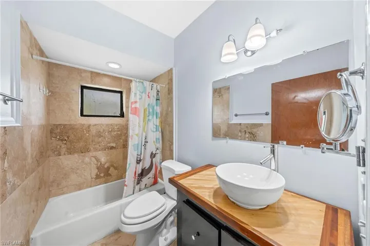 Full bathroom featuring toilet, shower / bath combo, and vanity