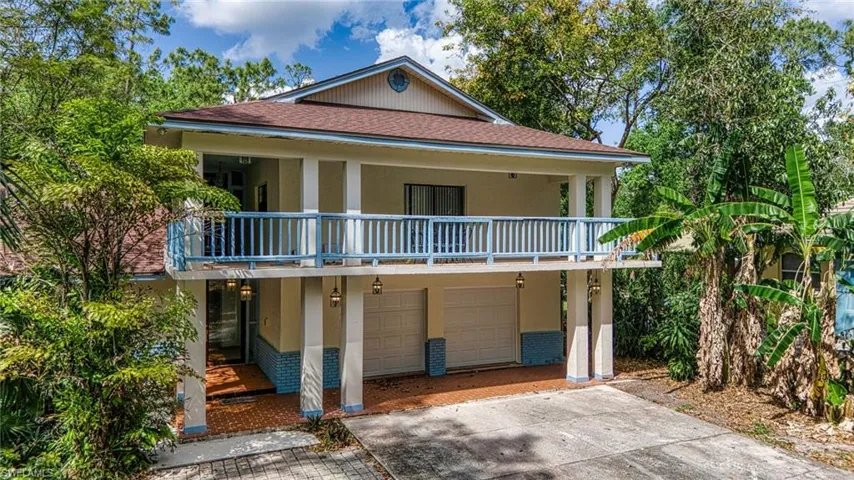 Coastal inspired home with a shingled roof, an attached garage, a balcony, brick siding, and stucco siding