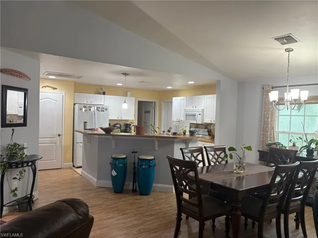 Dining area featuring lofted ceiling, light wood-style floors, a chandelier, and recessed lighting