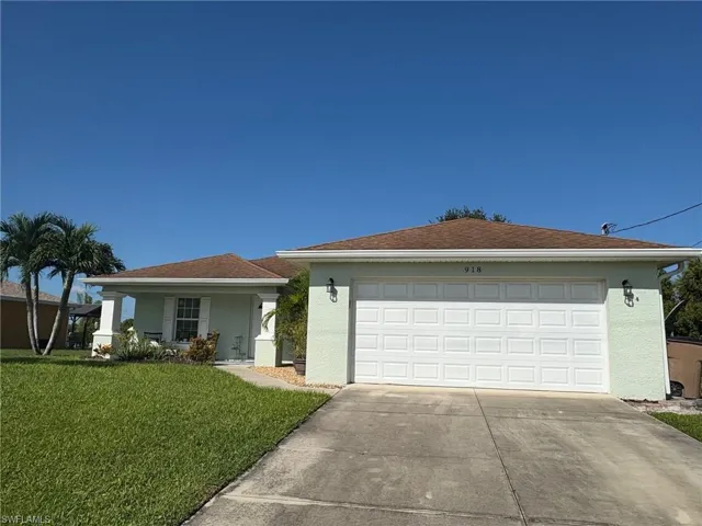 Ranch-style home with stucco siding, a front lawn, concrete driveway, a porch, and an attached garage