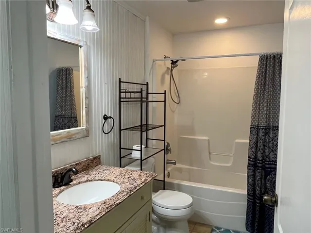Bathroom featuring vanity, shower / bathtub combination with curtain, tile patterned floors, and recessed lighting