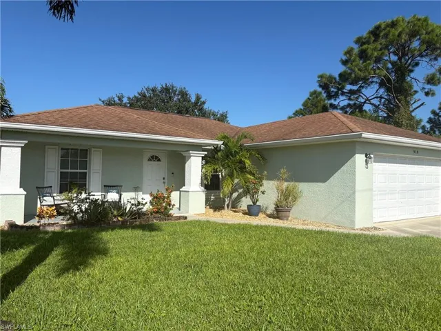 Ranch-style house featuring stucco siding, a front lawn, and a garage