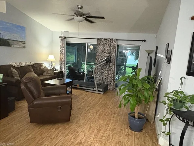 Living room with wood finished floors, ceiling fan, and vaulted ceiling