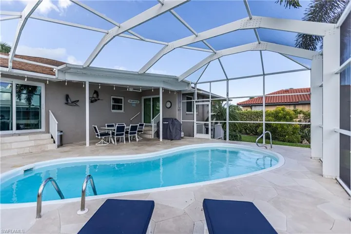 Swimming pool with a patio area, entry steps, area for grilling, and a lanai