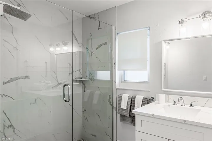 Bathroom featuring a marble finish shower and vanity