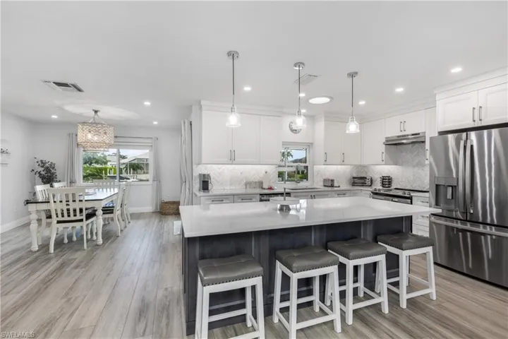 Kitchen with stainless steel appliances, a center island, decorative backsplash, white cabinets, and recessed lighting