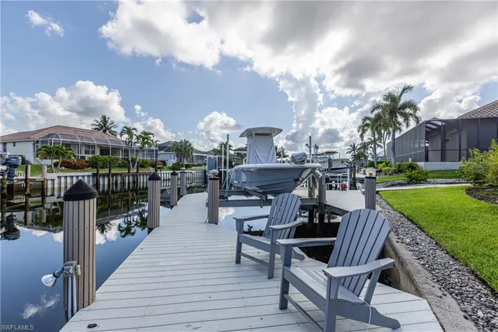 Dock area with boat lift, a water view, and a residential view