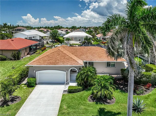 Mediterranean / spanish-style home with a residential view, a garage, stucco siding, a front lawn, and driveway