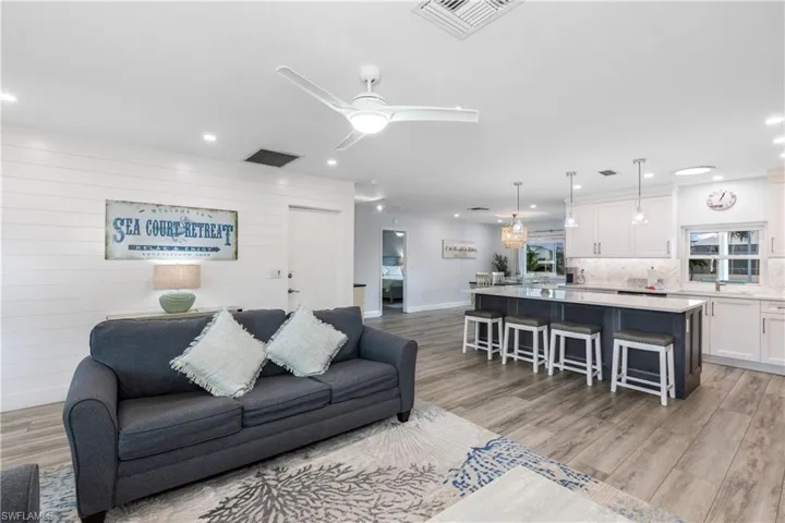 Living area with recessed lighting, light wood-style floors, a ceiling fan, and wood walls