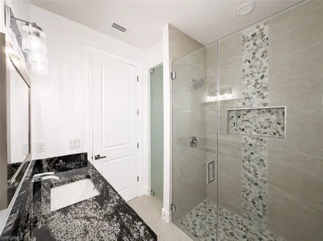 Modern bathroom featuring a frameless glass shower enclosure with pebble tile accents