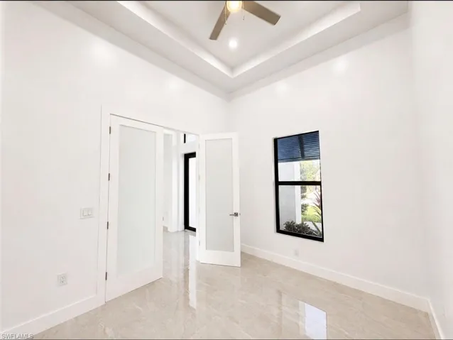 Bright room featuring white walls, a tray ceiling with recessed lighting, and a ceiling fan