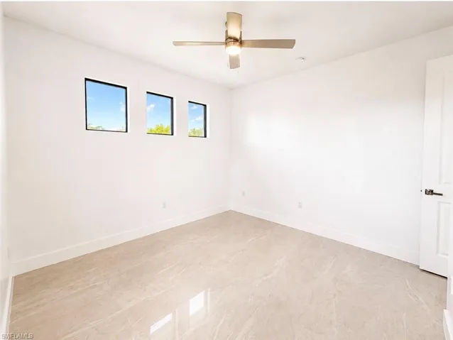 Room featuring light-toned tile flooring, three square windows with dark frames, and a modern ceiling fan with integrated lighting