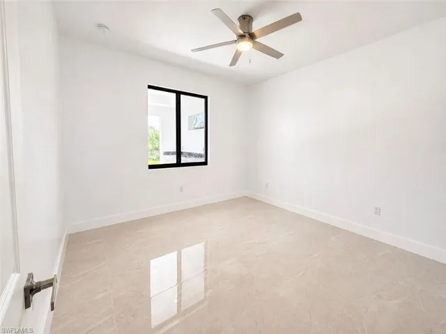 Bright interior space featuring large format rectangular tile flooring, a modern ceiling fan with integrated lighting, a black-framed window, and white baseboards