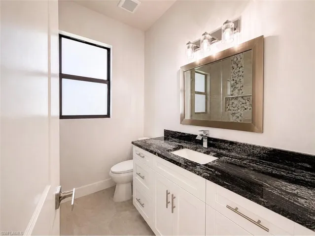Vanity featuring a dark stone countertop with integrated sink and chrome faucet