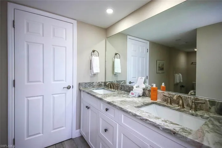 Bathroom with double vanity, wood finished floors, and recessed lighting
