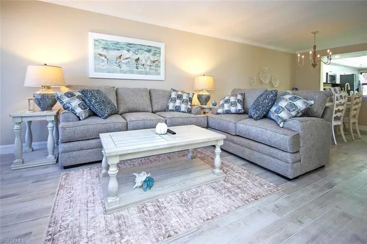 Living room with a chandelier, ornamental molding, and wood finished floors