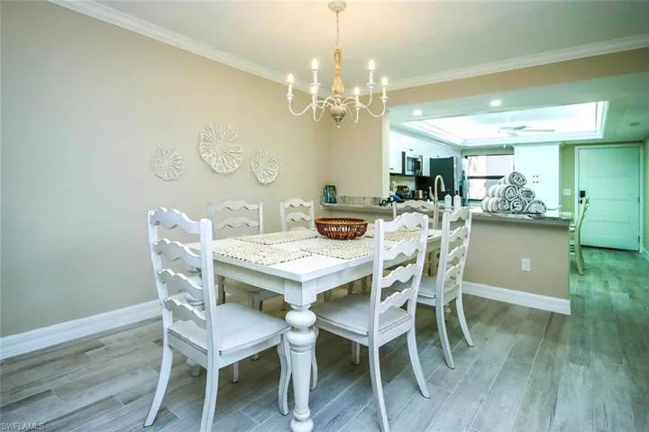 Dining room featuring a chandelier, light wood-style flooring, ornamental molding, and a raised ceiling