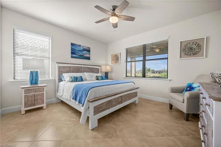 Bedroom with multiple windows, ceiling fan, and light tile patterned floors