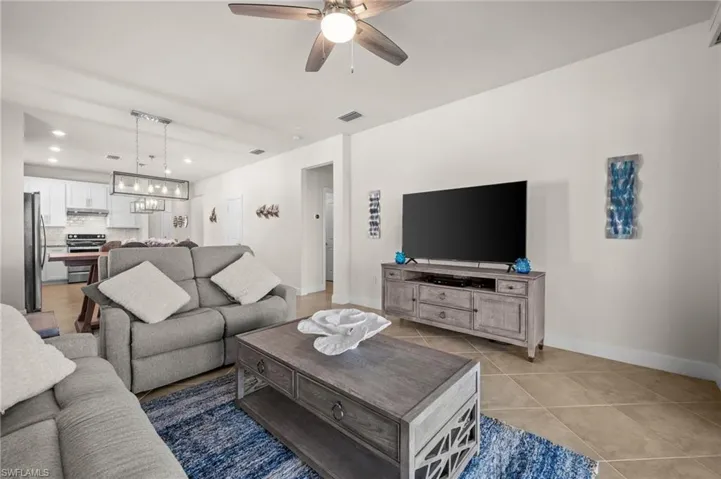 Living room with recessed lighting, a ceiling fan, light tile patterned floors, and a chandelier