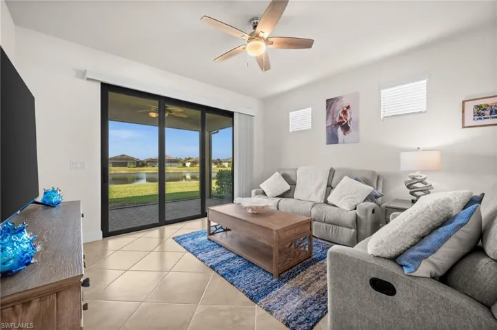 Living area featuring ceiling fan, light tile patterned floors, and a water view